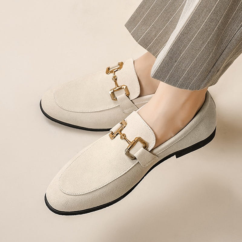 Cream-colored suede loafers for men with gold-tone horsebit buckles and black soles in khaki and black colors.