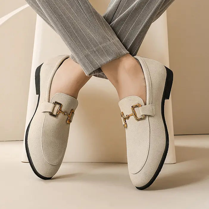 Beige suede buckle loafers for men with gold-tone horsebit buckles and black rubber soles in khaki color.