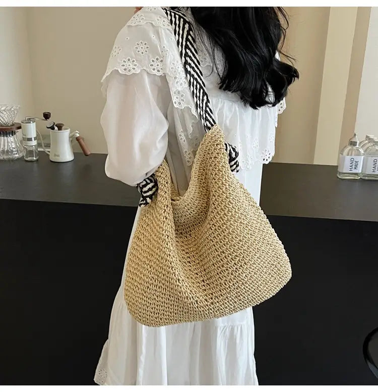 Beige woven straw tote bag with a black and white striped bow handle.