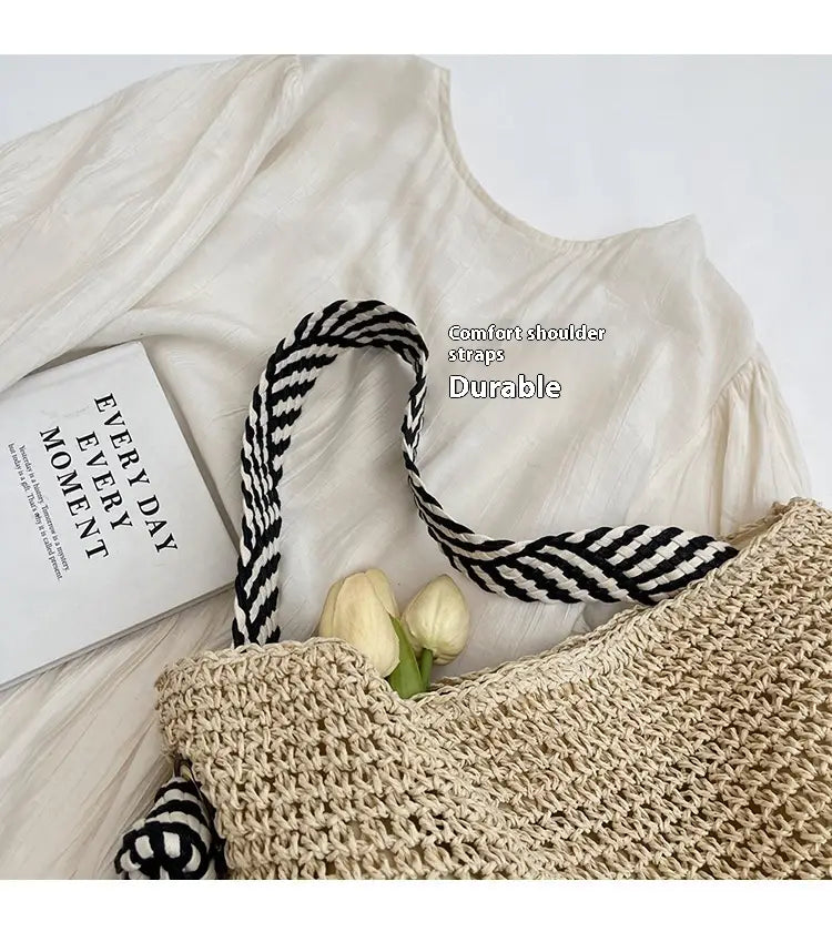 Beige woven straw tote bag with black and white striped shoulder straps featuring a striped bow handle.