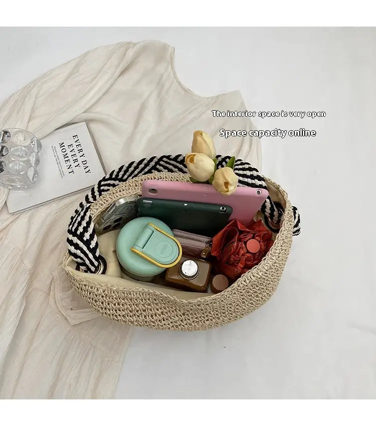 beige woven straw tote bag with black and white striped bow handles designed for stylish carrying.