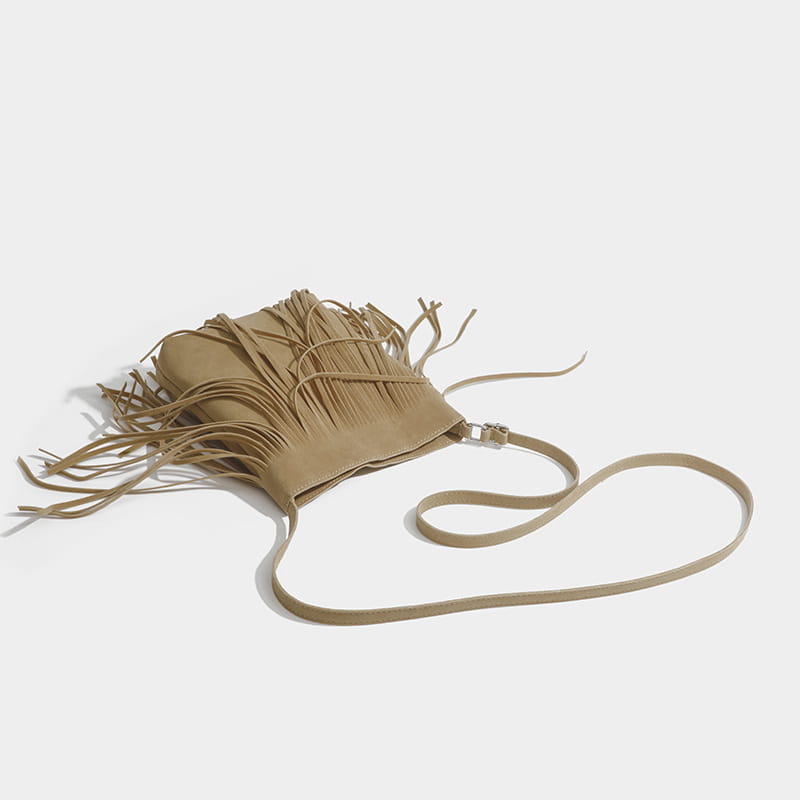 A maroon suede fringe crossbody bag with a long adjustable strap for artistic tassel canvas shoulder bag travel use.