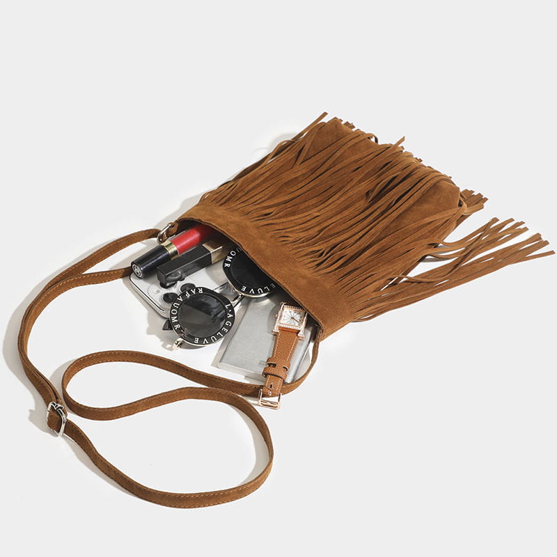 A maroon suede fringe crossbody bag with a long adjustable strap for artistic tassel canvas shoulder bag travel use.