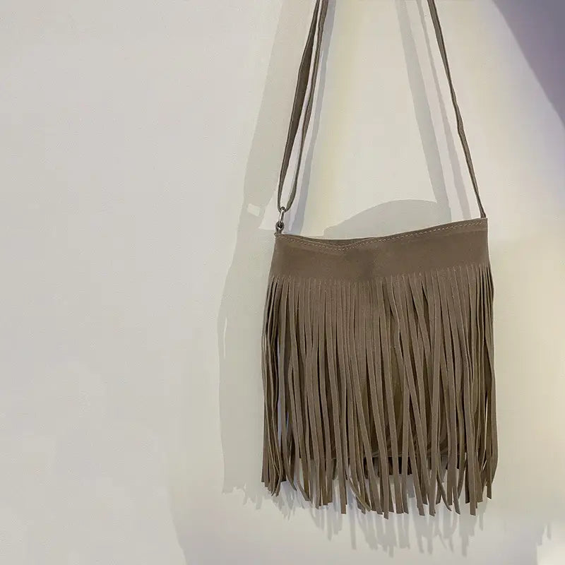 A maroon suede fringe crossbody bag with a long adjustable strap for artistic tassel canvas shoulder bag travel use.