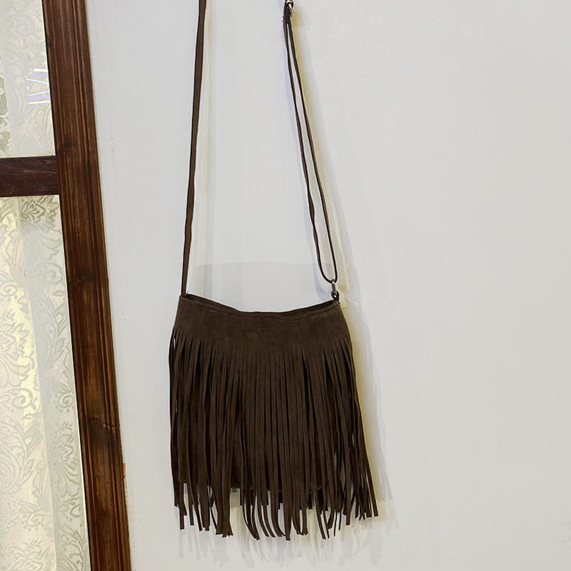 A maroon suede fringe crossbody bag with a long adjustable strap for artistic tassel canvas shoulder bag travel use.