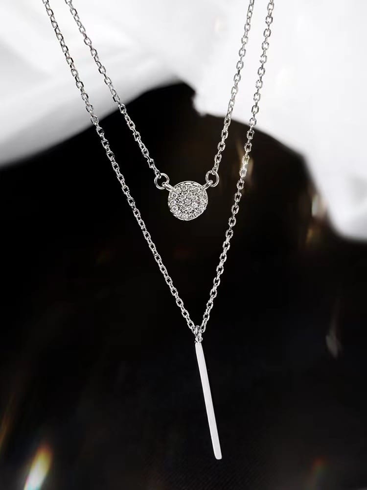 Double layer silver pave zircon necklace featuring a round charm and a sleek vertical bar pendant.