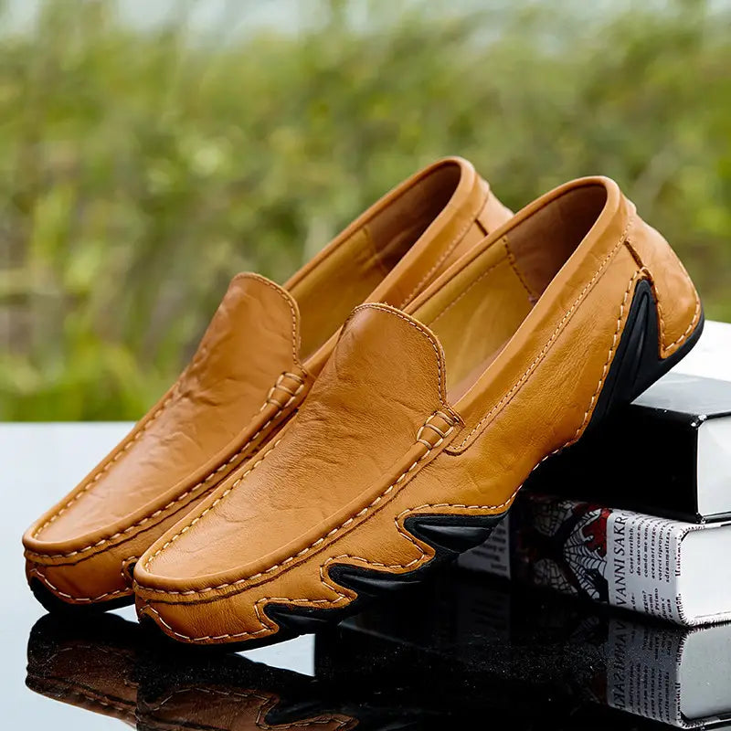 Mocasines de cuero color camel para hombres con estilo británico retro, con acentos de goma negra en los laterales y las suelas.