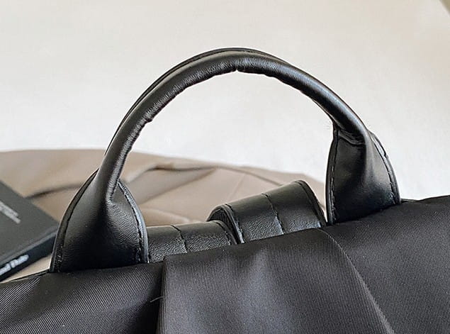 black leather handle with stitched edges and padded grip on waterproof large capacity nylon travel backpack with pu leather trim