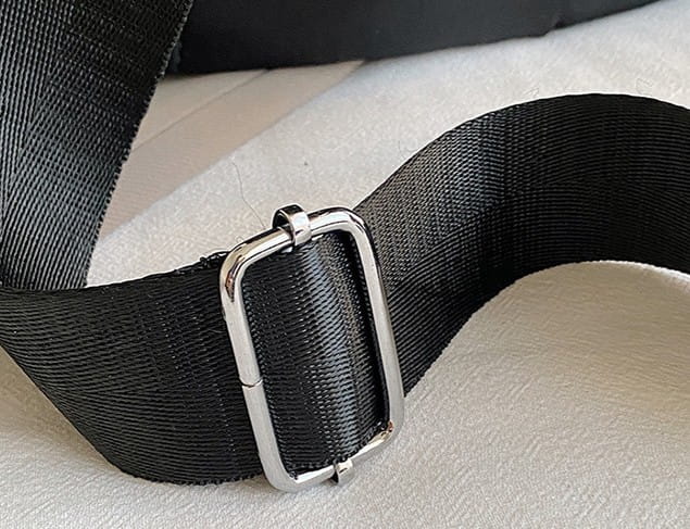 black woven strap with a sleek silver-toned rectangular buckle on a waterproof large capacity nylon travel backpack with pu leather trim