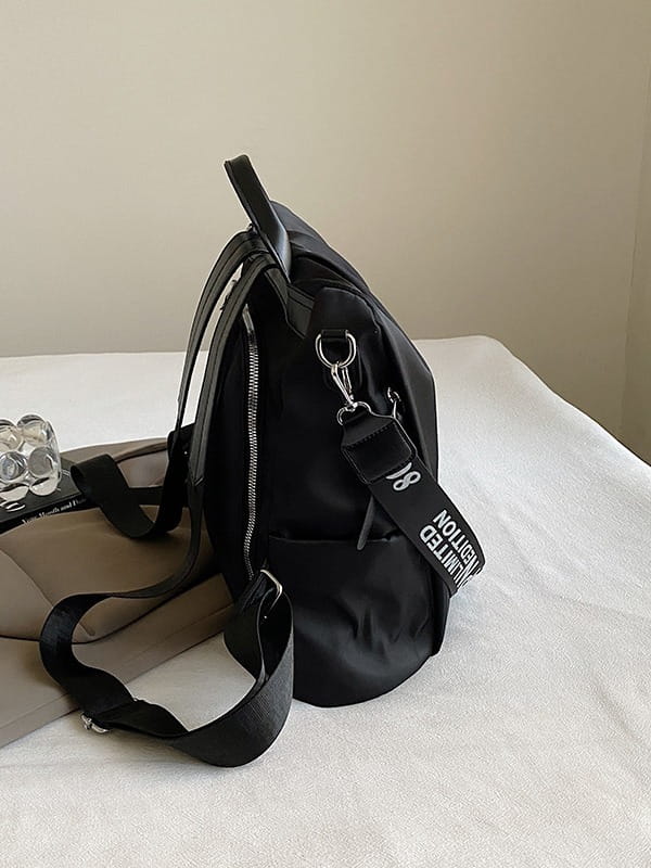 Black nylon waterproof large capacity travel backpack with pu leather trim featuring adjustable shoulder straps and a detachable strap with white text shown from the back side.