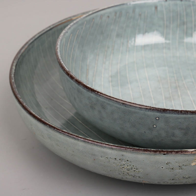 Set of two light blue ceramic bowls with textured slightly distressed rims and subtle vertical striations inside from a ceramic dinnerware set retro ribbed plates and bowls.