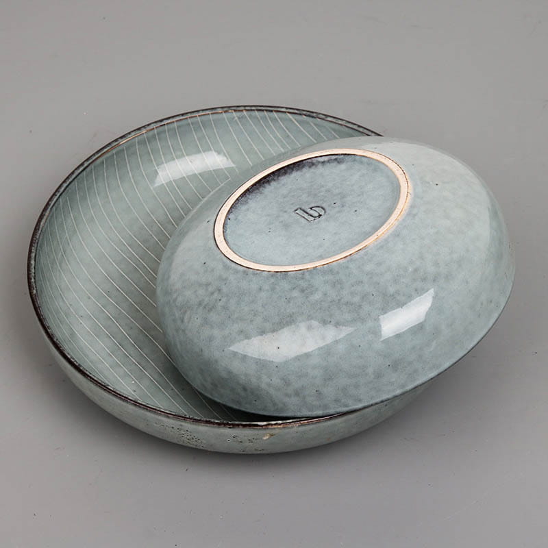 A sleek light blue ceramic bowl with subtle vertical striations and a glossy finish rests inside a matching larger dish from the ceramic dinnerware set retro ribbed plates and bowls.