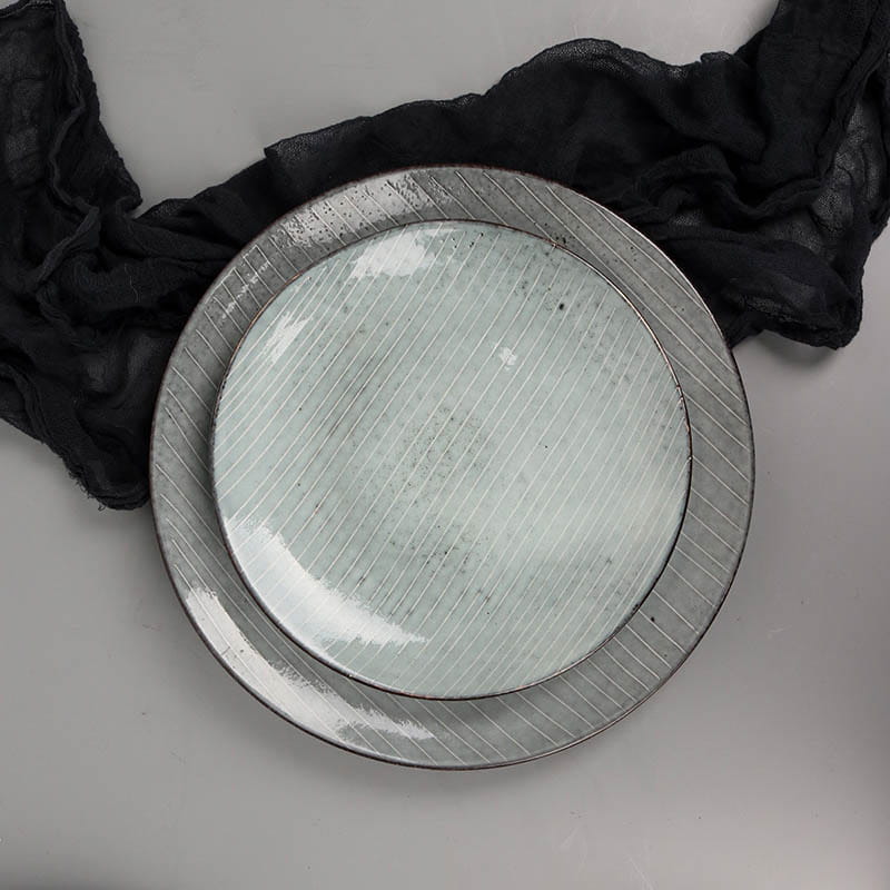 A pair of ceramic dinnerware set retro ribbed plates with a matte silver finish and subtle diagonal ridges featuring an inner plate in soft mint green glaze.