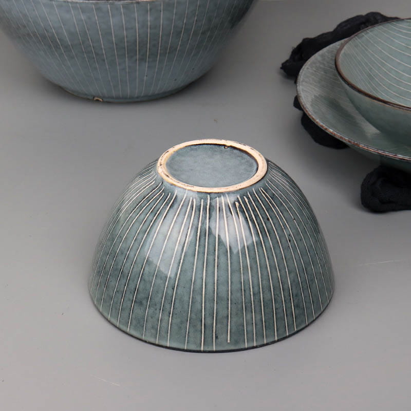A ceramic bowl from the retro ribbed plates and bowls set with a matte teal glaze, fine vertical white stripes, and a gold-rimmed base.