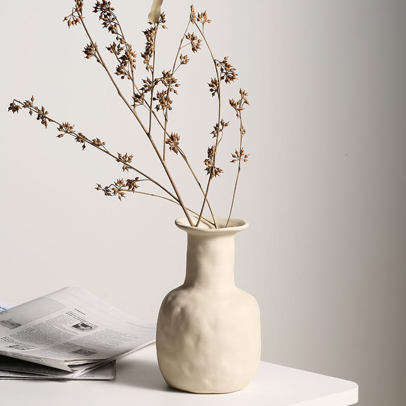 Cream-colored ceramic vase with a textured handcrafted surface and slender neck in minimalist Scandinavian pottery style.