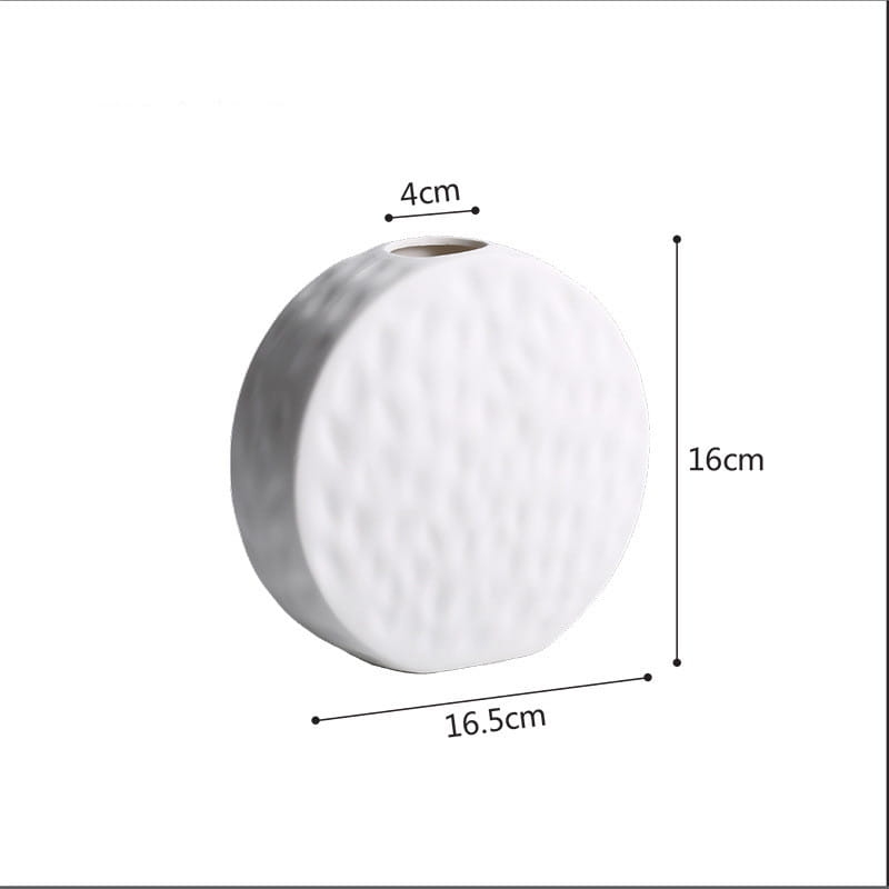 A white ceramic vase with a textured hammered surface and rounded shape featured as a minimalist Scandinavian pottery piece.