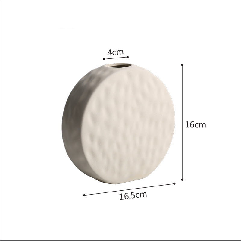 Cream-colored ceramic vase with a textured hammered surface and rounded silhouette designed in minimalist Scandinavian style.