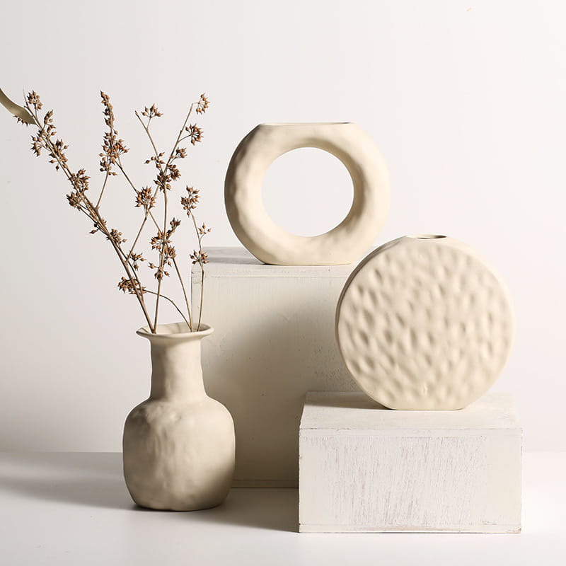 Cream-colored ceramic vases featuring minimalist Scandinavian textured pottery with organic handcrafted shapes.