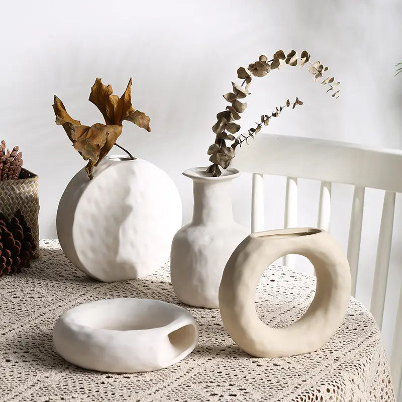White ceramic vases with textured organic shapes and minimalist Scandinavian pottery design.
