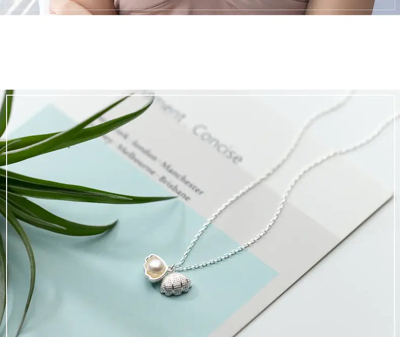 Personalized s925 silver shell and pearl pendant necklace featuring a silver seashell pendant with a pearl nestled inside and a smaller textured shell charm attached below.