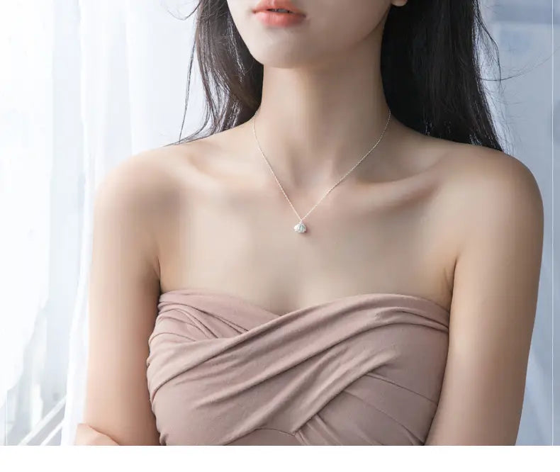 A delicate personalized s925 silver necklace featuring a small round shell and pearl pendant with sparkling stones.