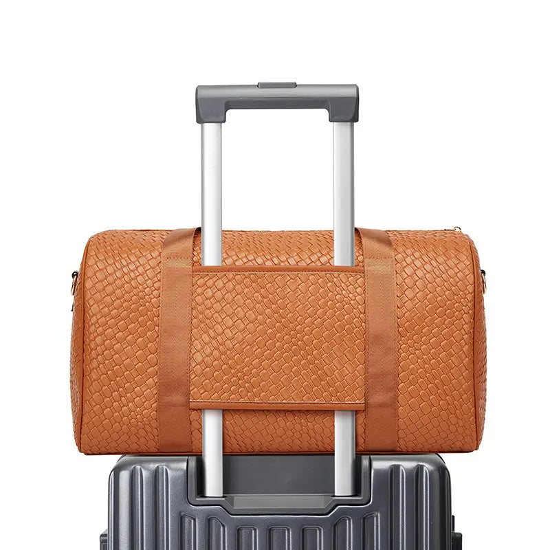 Sac de sport cabas de voyage en cuir beige à texture tressée avec une poignée robuste et des sangles assorties, conçu pour se fixer au-dessus d’une valise, issu de l’ensemble de voyage d’affaires en 3 pièces pour la salle de sport.