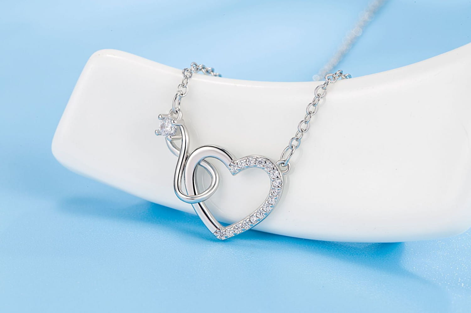 Silver heart-shaped pendant necklace in 925 sterling silver with a delicate chain and sparkling clear pave crystals along the outline.