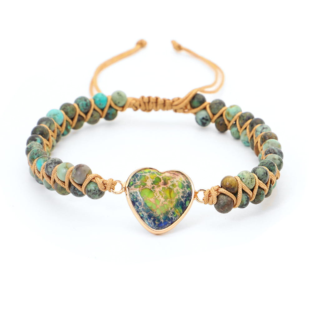Handmade woven heart stone pendant bracelet featuring a heart-shaped turquoise stone with a gold-tone frame centered on a braided cord bracelet with earthy green and blue beads.