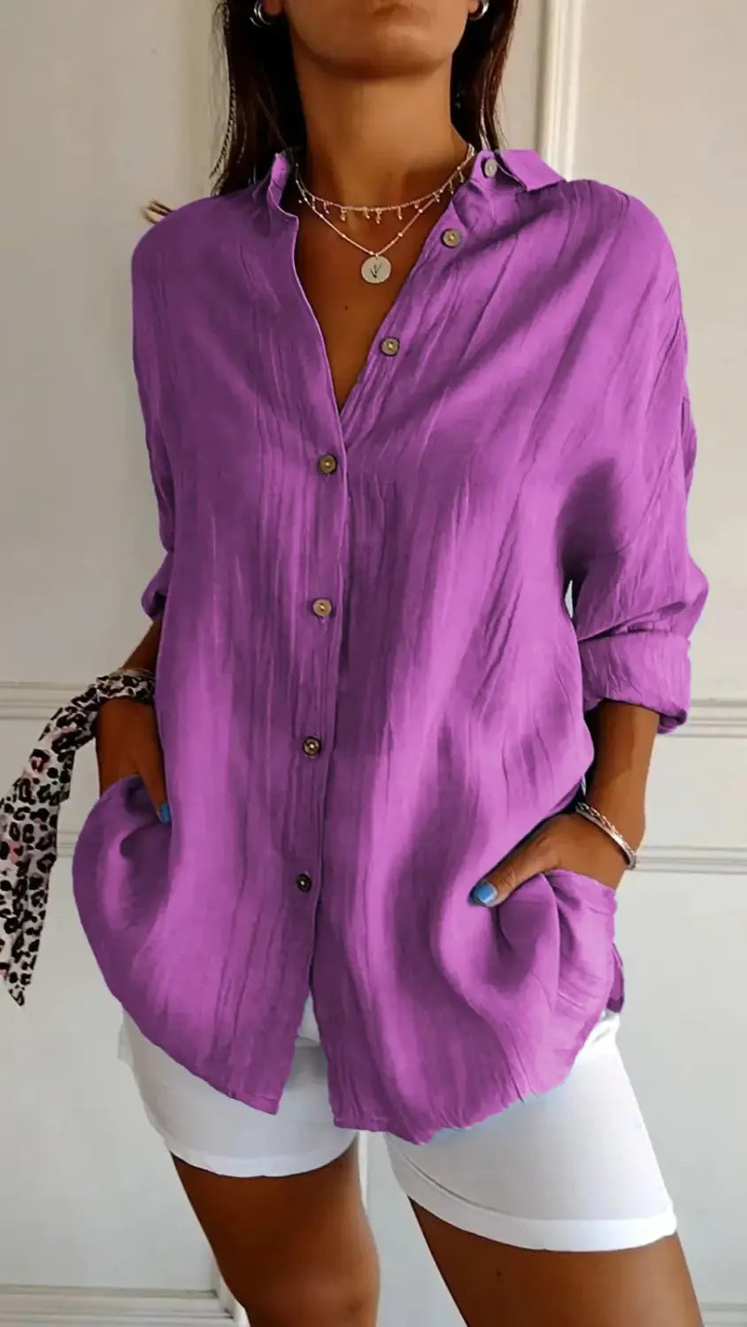 A vibrant purple women’s relaxed pleated button up shirt made of subtle textured fabric with rolled sleeves and a loose fit.