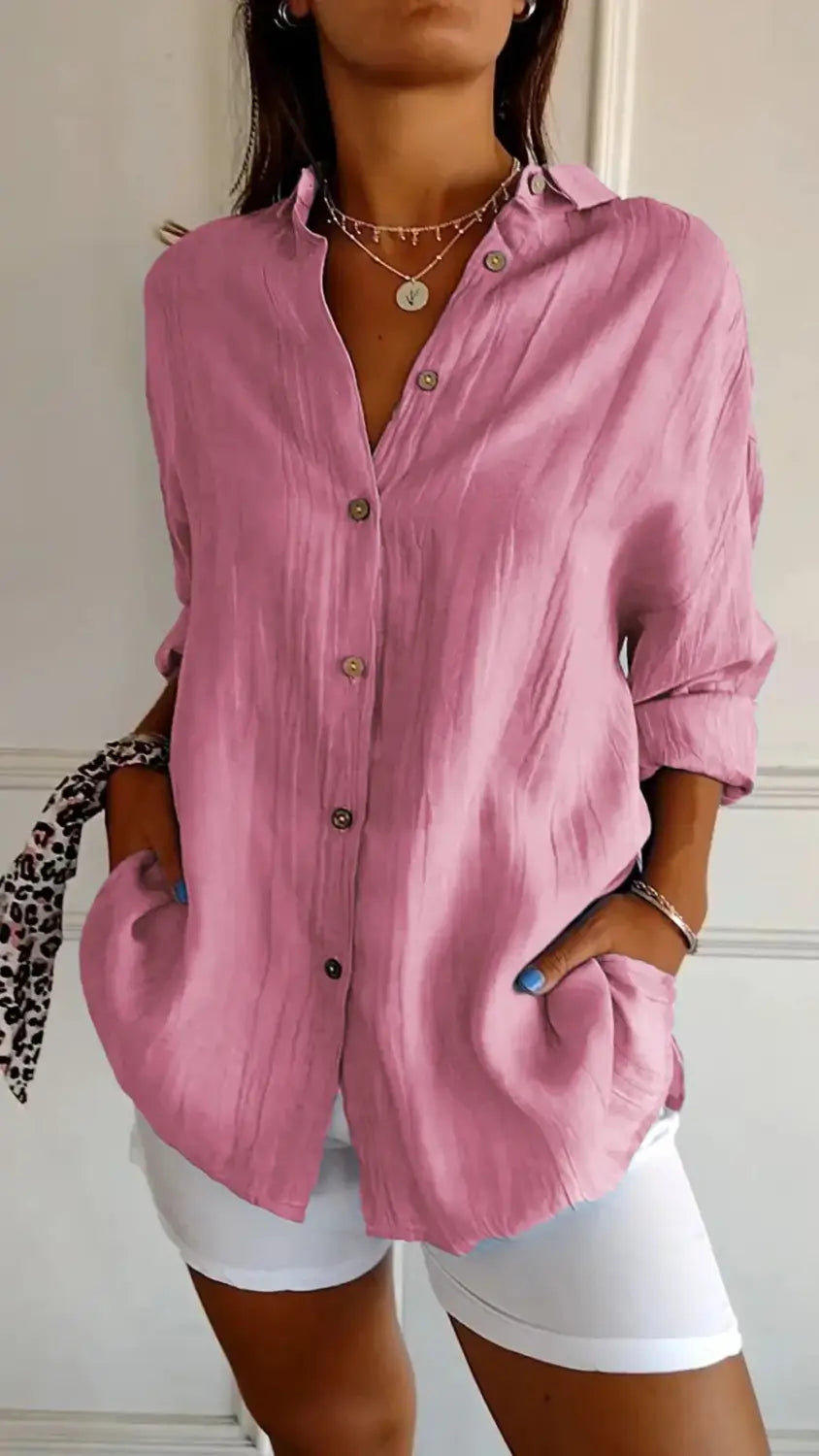 A soft pink women’s relaxed pleated button up shirt with rolled sleeves and subtle textured fabric in a loose fitting design.