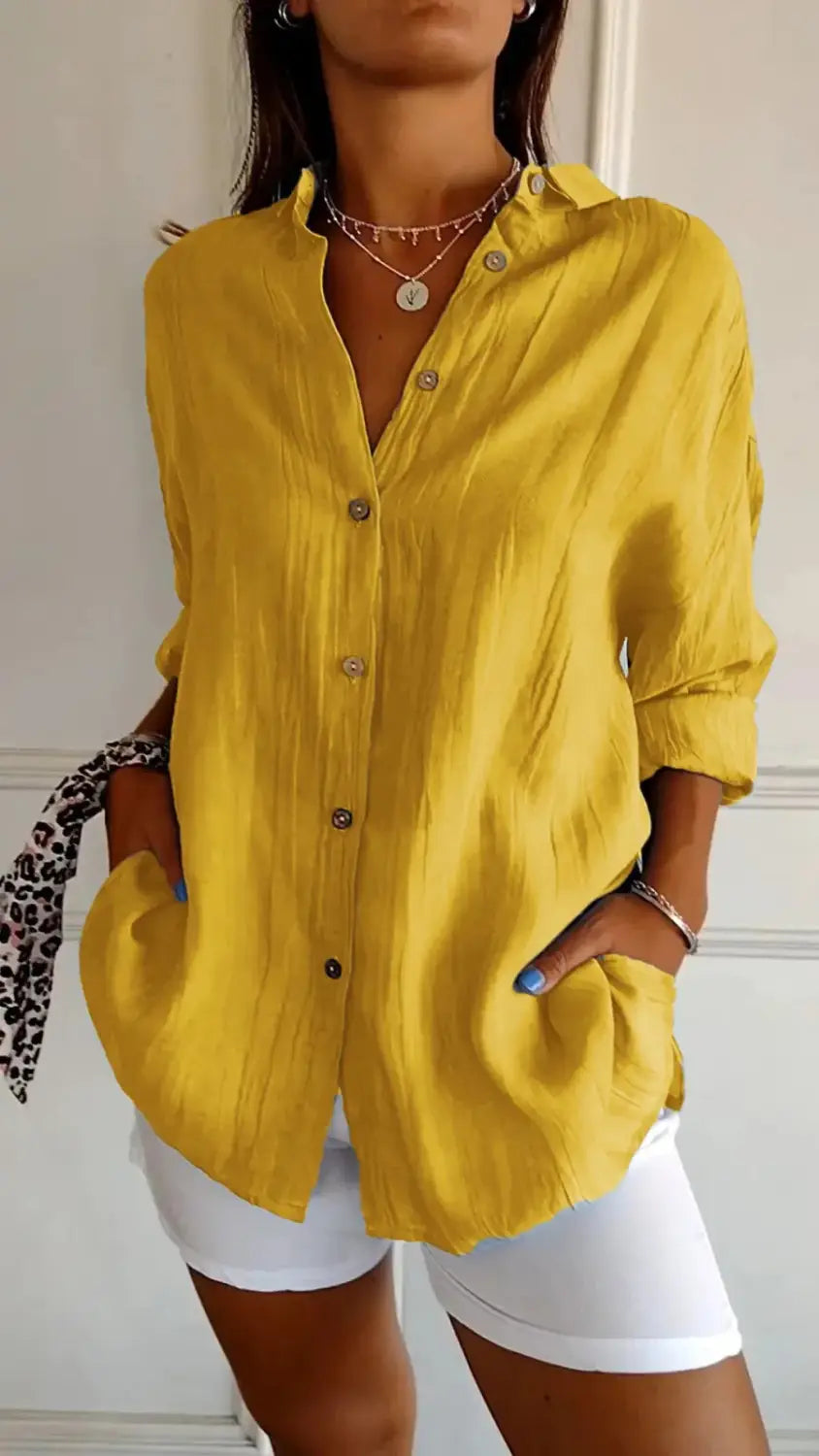 A vibrant yellow women’s relaxed pleated button up shirt with rolled sleeves and subtle textured fabric.