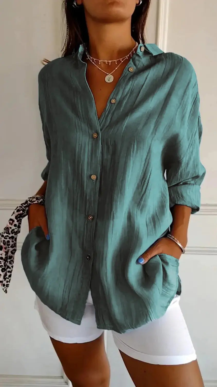 Women’s relaxed pleated button up shirt in teal with rolled sleeves and subtle textured fabric.
