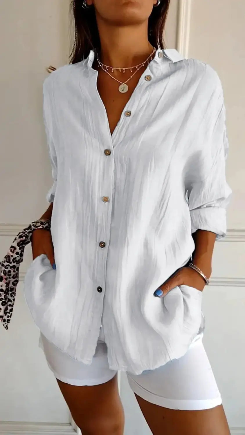 White relaxed pleated women’s button up shirt with rolled sleeves and subtle textured fabric.