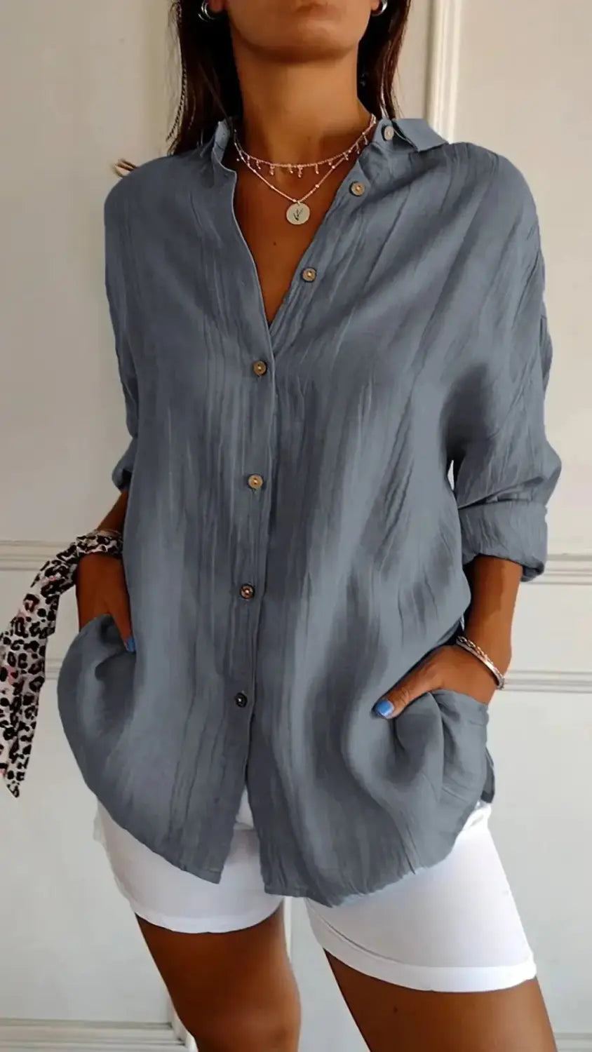 A soft light blue women’s relaxed pleated button up shirt with rolled sleeves made from breathable fabric.