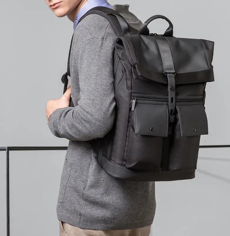 men’s 16 inch roll top laptop backpack in black nylon with leather trim and front pockets.