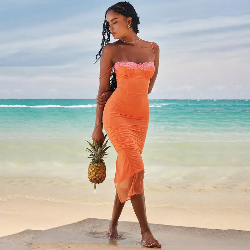 Ein lebhaftes Midikleid aus orangefarbenem Spitzeinfasstungs-Mesh mit trägerlosem Oberteil mit Spitzendetails und einem gerafften transparenten Overlay-Rock.