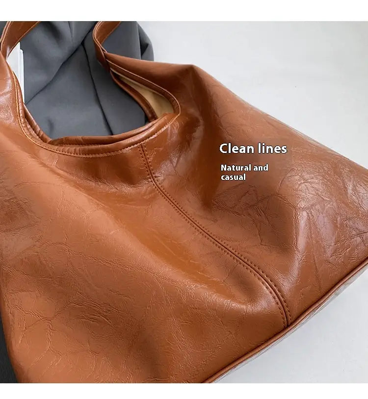 Eine hellbraune Vintage-Leder-Tragetasche aus Kunstleder mit großer Kapazität und klaren, minimalistischen Linien, entworfen als Schulterhandtasche.