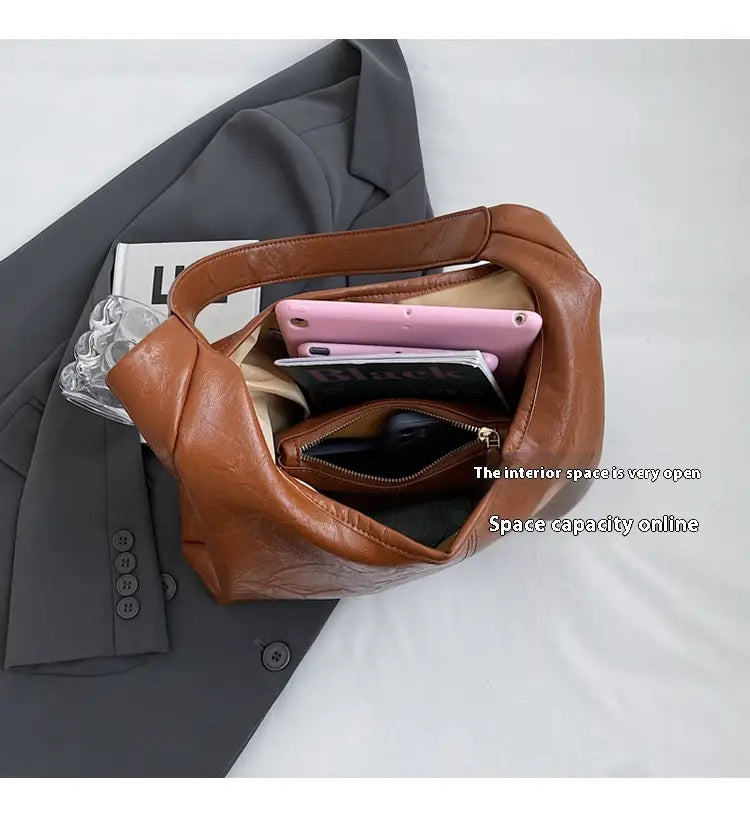 Braune Vintage-Leder-Tragetasche mit geräumigem Innenbereich und sichtbaren Reißverschlüssen, entworfen als Schulterhandtasche mit großer Kapazität.