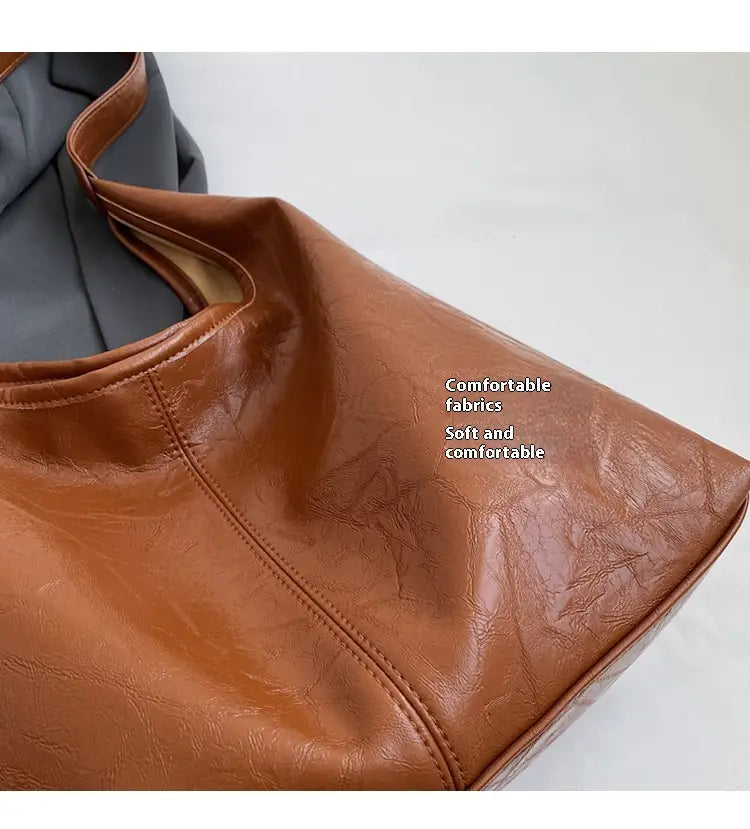 Vintage-Leder-Tragetasche mit großer Kapazität als Schulterhandtasche aus braunem Leder mit sichtbaren Nähten und einer leicht verknitterten Textur.