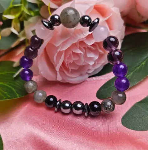 A natural amethyst and magnetic stone beaded unisex bracelet featuring alternating purple amethyst, gray moonstone, and black obsidian beads with a central silver-toned disc accent.