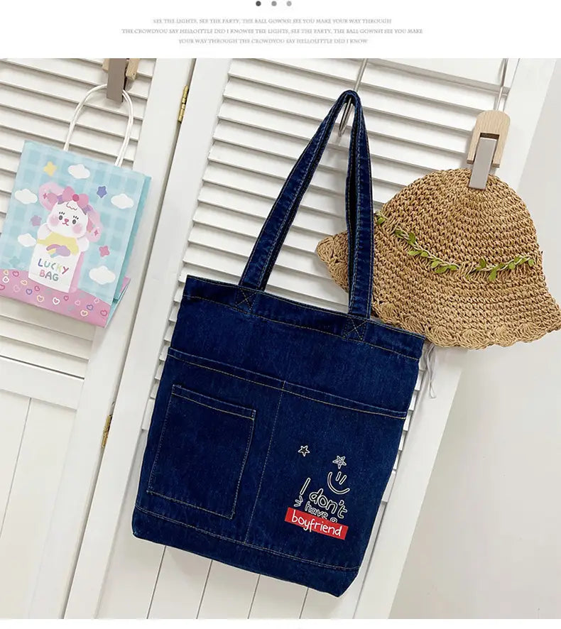 Blue denim tote bag with embroidered i dont need a boyfriend slogan and star design featuring a soft handle for comfortable carrying.