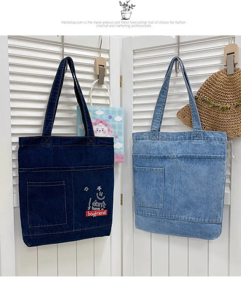 Two embroidered denim tote bags with soft handles in dark blue featuring an i dont need a boyfriend patch and light blue.