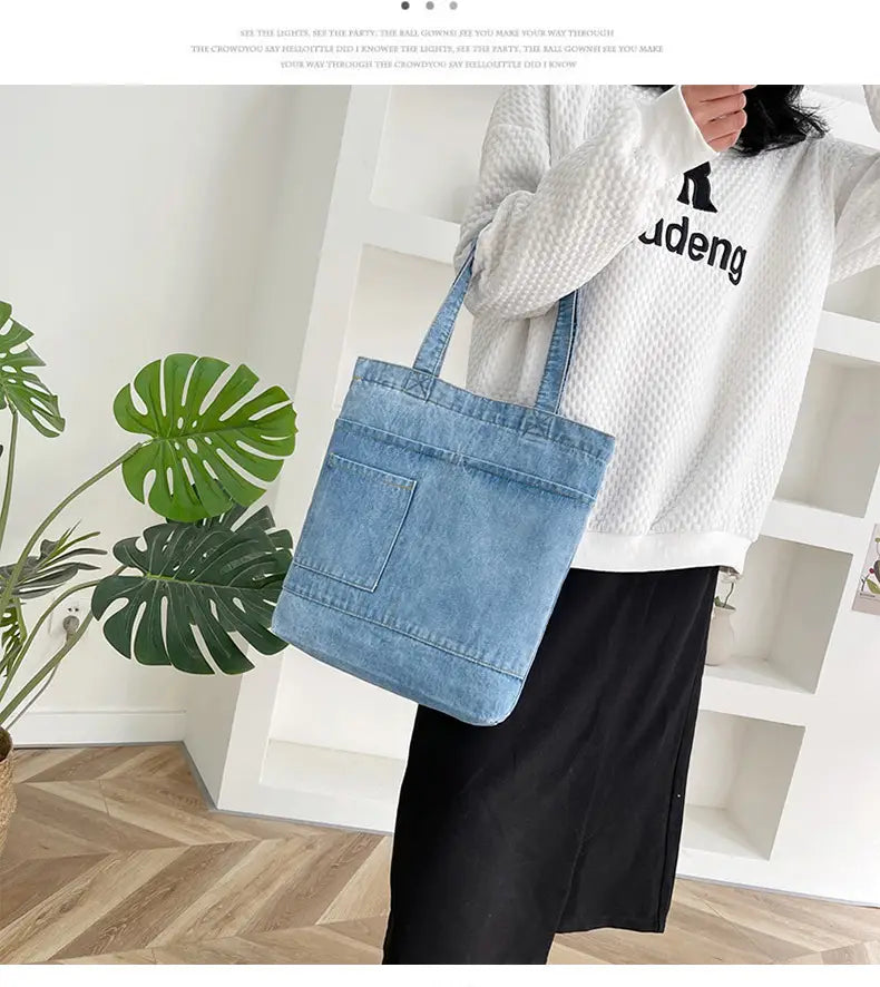 Blue denim tote bag with embroidery slogan, front pocket, and soft, sturdy handles.
