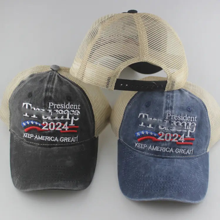 Two distressed trucker hats in dark gray and faded blue denim featuring embroidered president trump 2024 text with a red white and blue banner design titled Trump 2024 embroidered trucker hat.