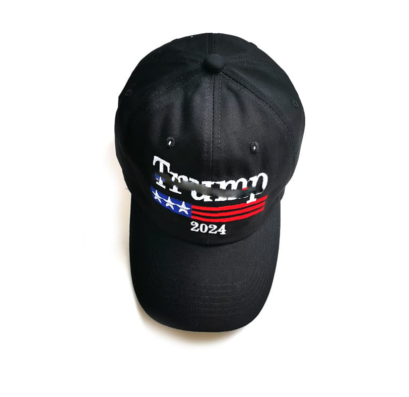 Black baseball cap with embroidered Trump 2024 logo featuring white lettering and a stylized American flag design in blue and red stripes on a trucker hat.