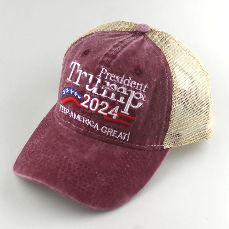 Maroon and beige embroidered Trump 2024 trucker hat with American flag motif and keep America great slogan.
