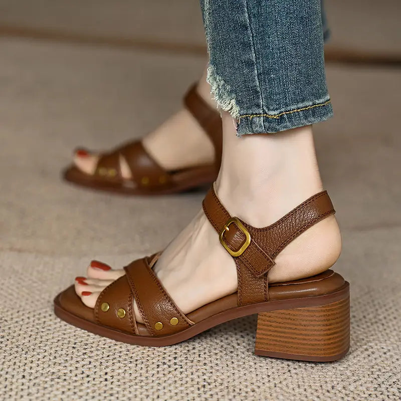 sandalias retro de estilo francés para mujer de cuero marrón, con tacones bloque de madera robustos y detalles de hebilla de tono dorado.