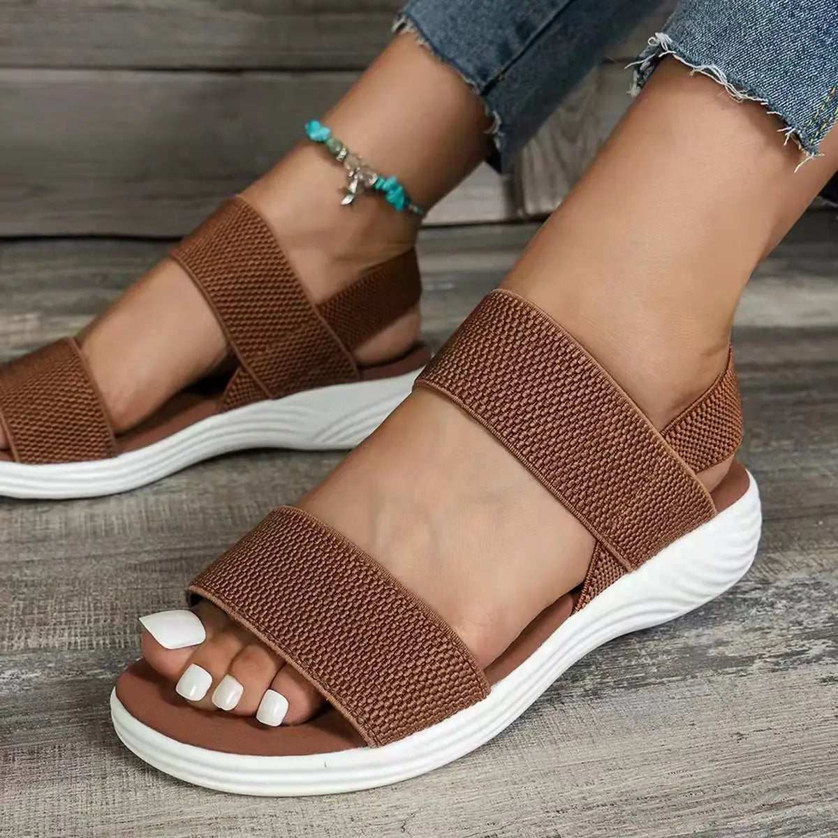 brown woven strap flyknit elastic back strap flat sandals for women with white cushioned sole displayed from the back side