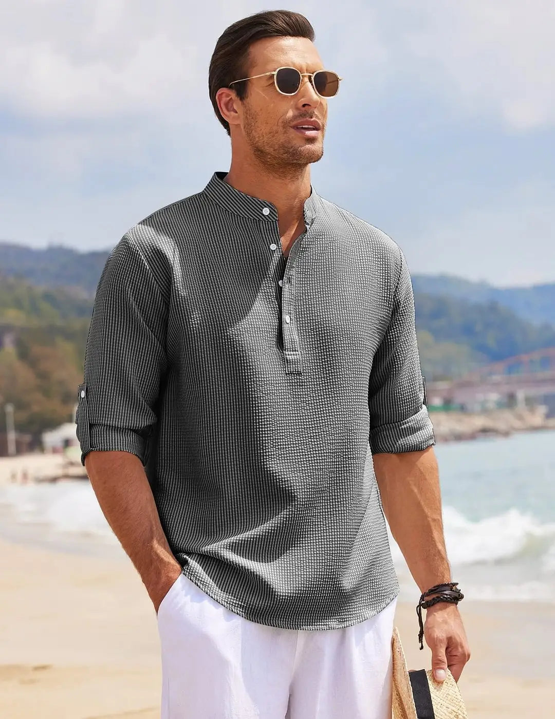 A man wearing a dark gray men’s casual ribbed cotton blend stand collar shirt with fine vertical stripes and rolled cuffs.