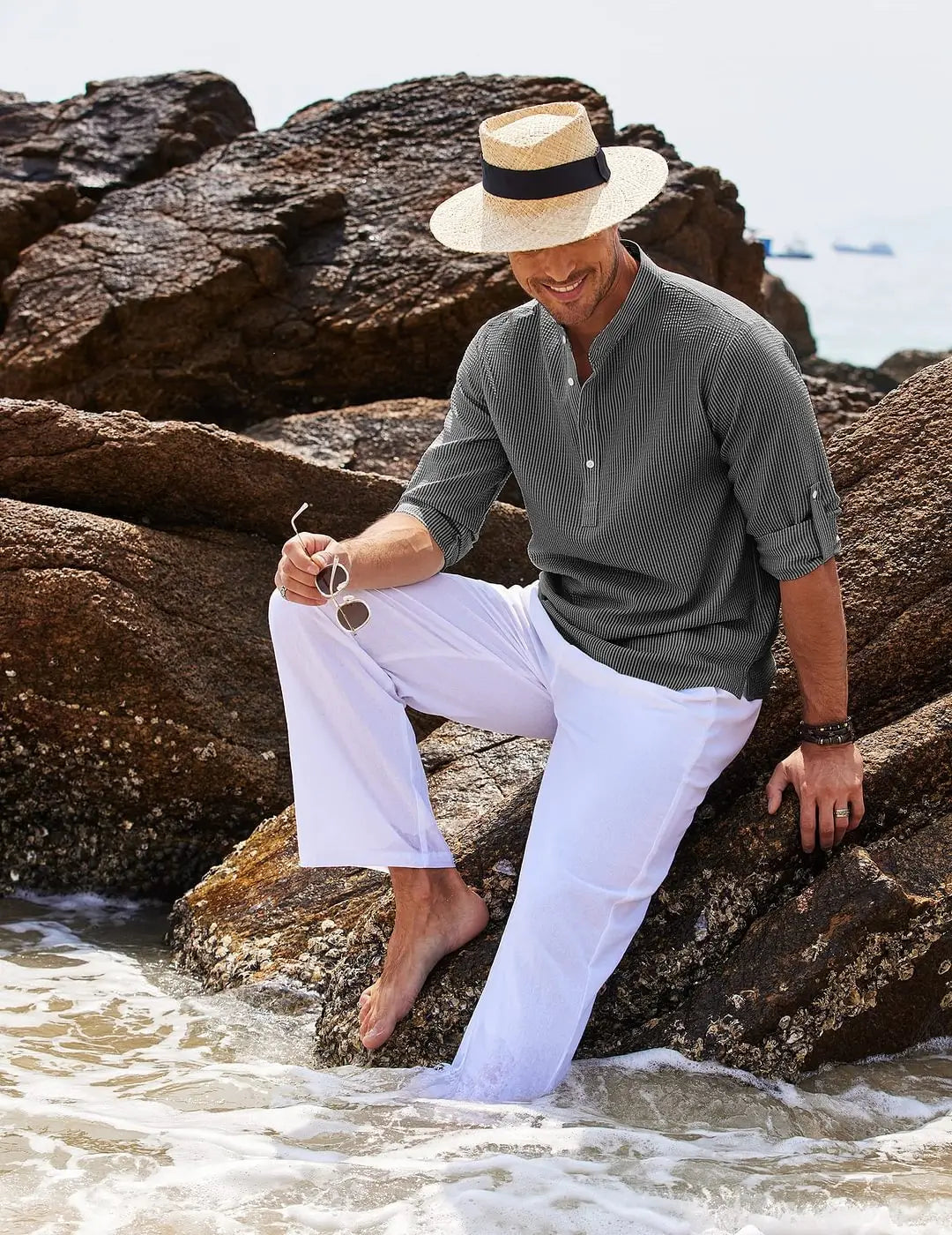 man wearing a gray striped ribbed cotton blend stand collar shirt paired with white trousers and a straw hat with black band